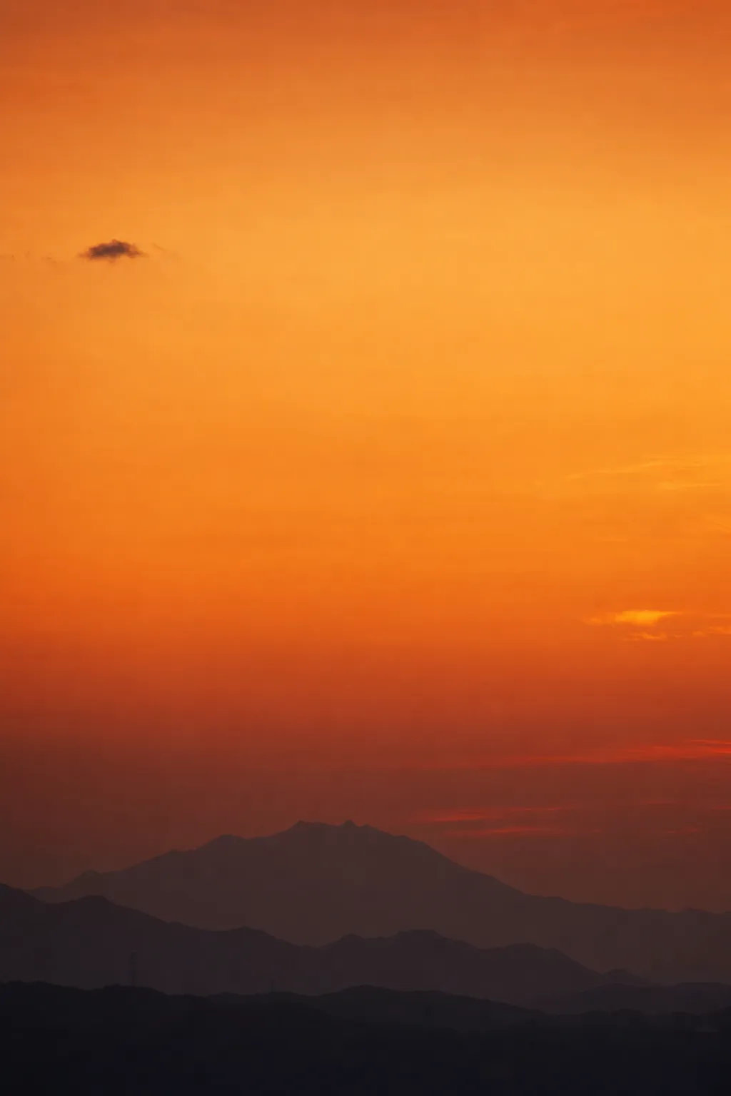 橙色に燃える夕暮れの空と、幾重にも重なる山の稜線